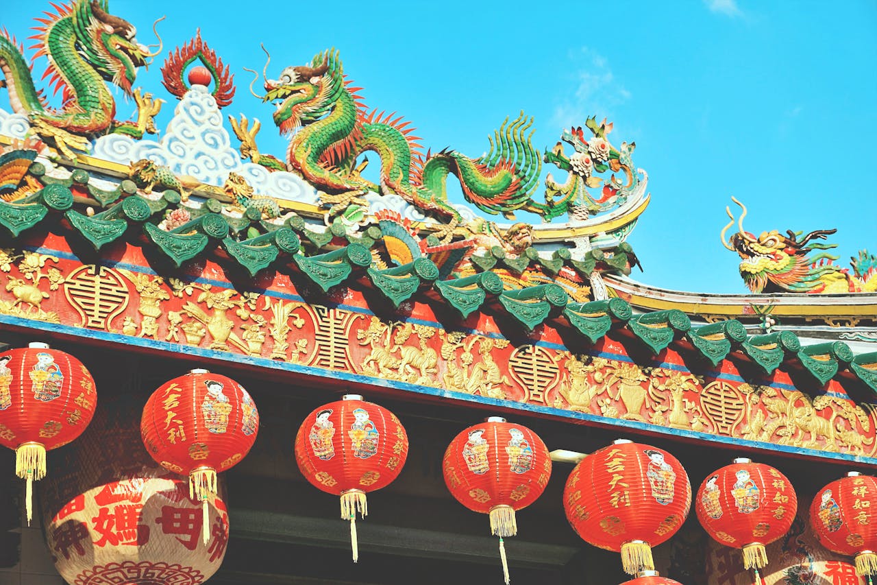 Vibrant Chinese temple rooftop with dragons and lanterns in Bangkok, Thailand.