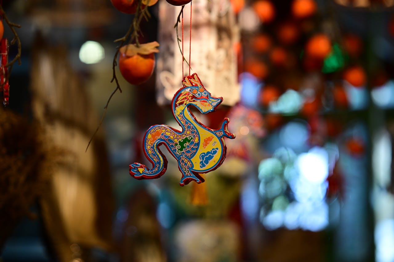 Vibrant Chinese dragon ornament hanging with blurred festive background.