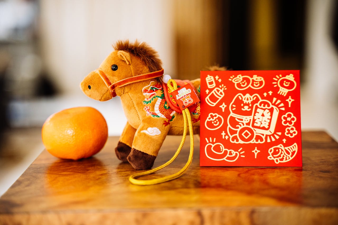 Celebrate Lunar New Year with a toy horse, orange, and festive red packet.