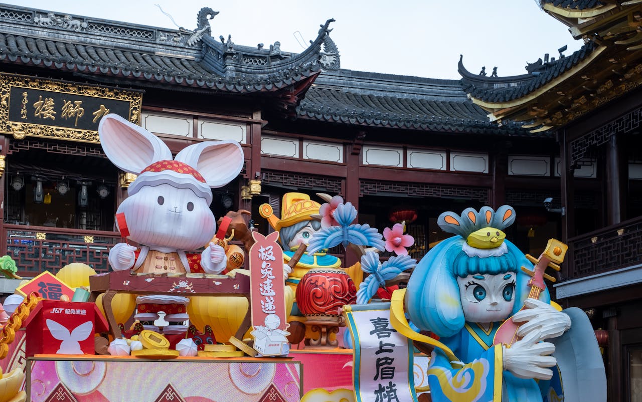 Colorful Chinese New Year figures and decorations in front of traditional temple.